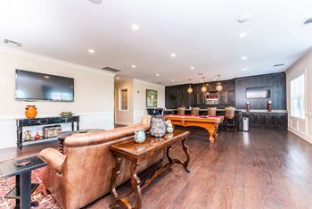 Resident social lounge with oversized sofa, TV, communal kitchen and pool table at Riverstone apartments in Macon, GA